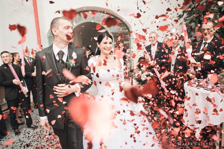 Šťastný novomanželia po sobáši červené srdiečkové konfety